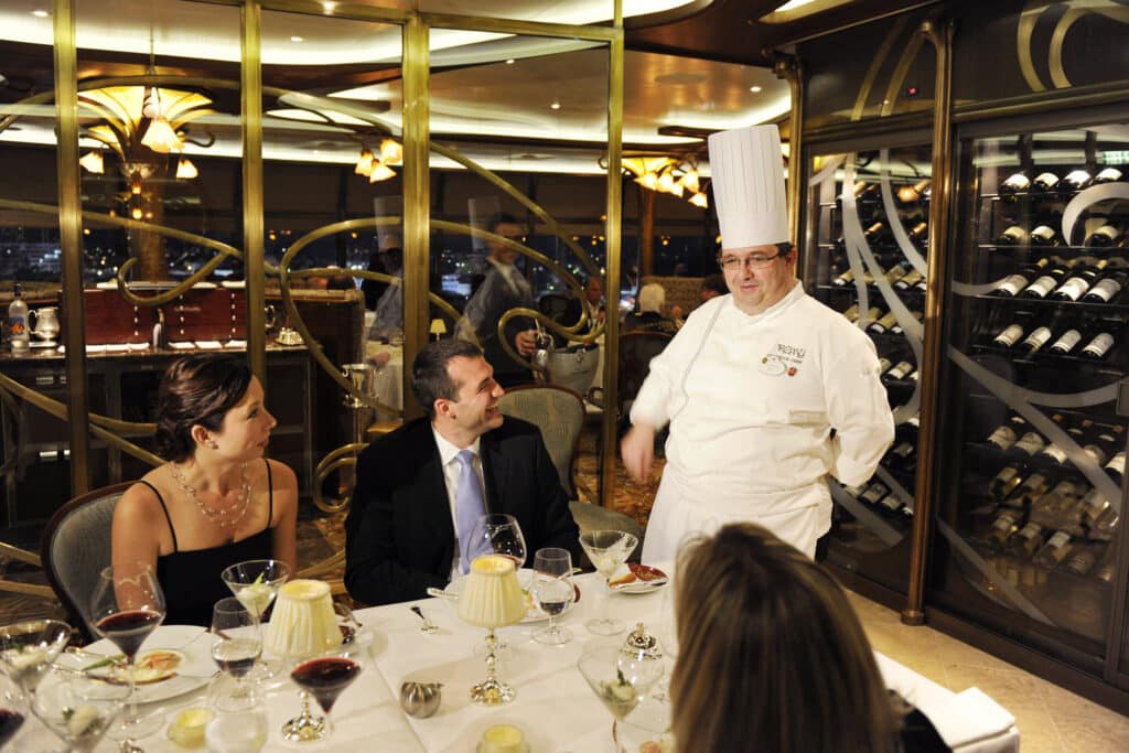 A chef standing and serving people at a cruise ship dining hall