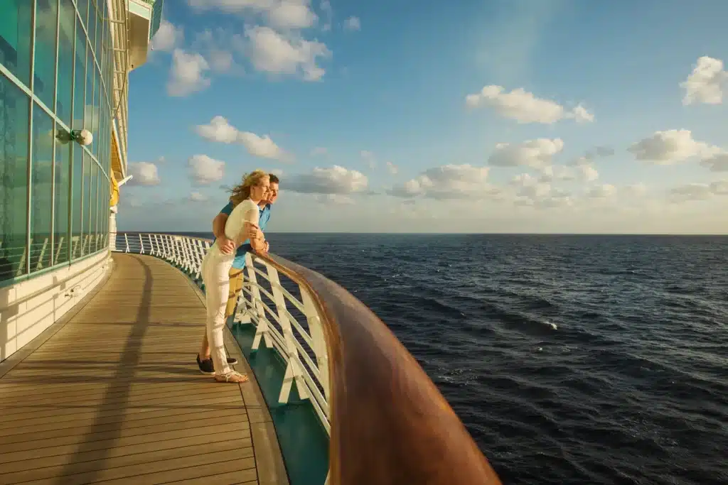 A couple looking at the sea standing on the rails of a cruise ship