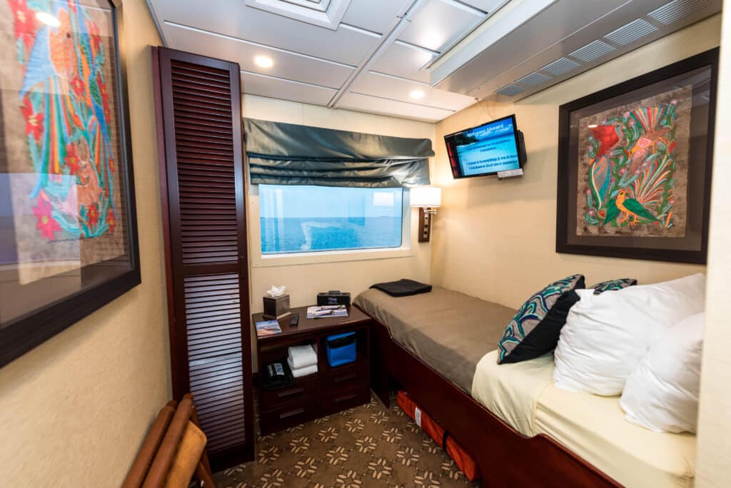 solo cabin on a cruise ship with wall art items placed on side table and cushions