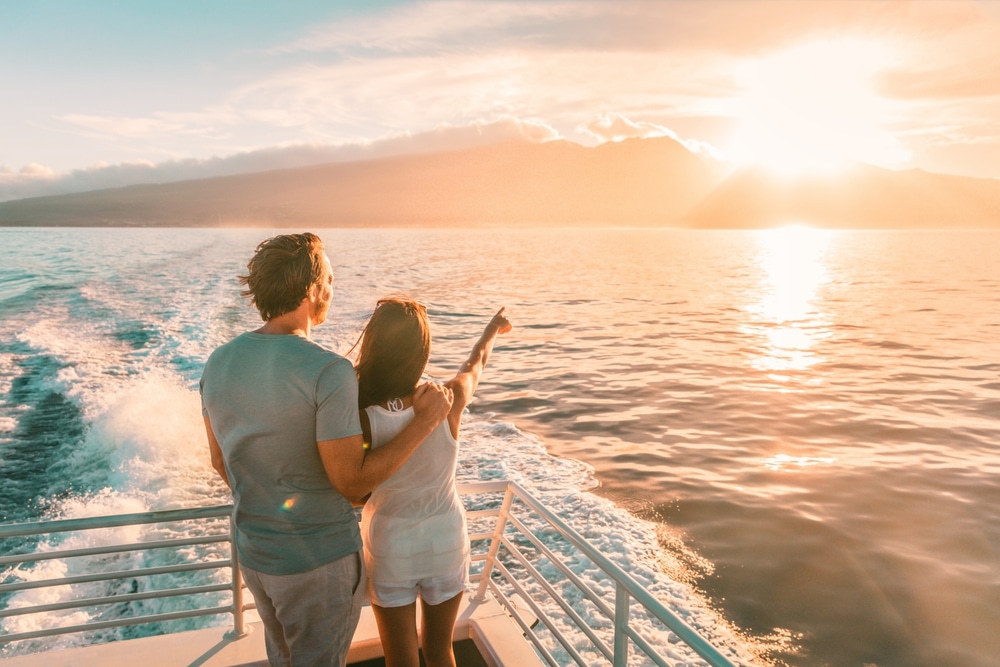 a couple standing on a cruise deck viewing evening sunset