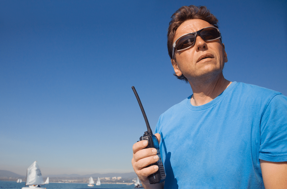 a man having a walkie talkie in his hand standing at the cruise ship